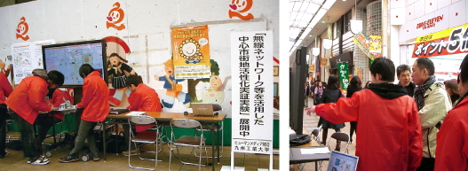 （写真）2009年1月、小倉魚町商店街で実施された「北九州市インテリジェントエリア実験」の様子。商店街の一角に設けた実験ブースにて、参加した学生らがパソコンを操作している。
